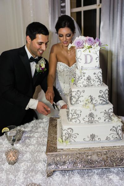The couple cut their five-tiered square wedding cake decorated with fresh roses and orchids