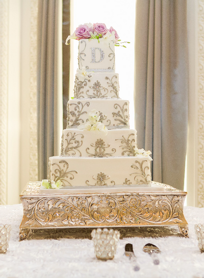 Five-Tiered square wedding cake decorated with fresh roses on silver cake stand