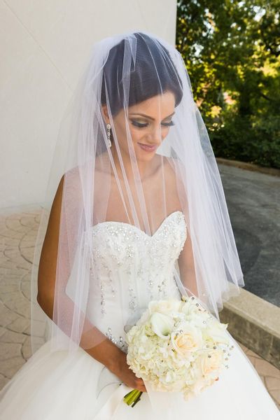 The bride's beauty portrait while she holds her all white rose, hydrangea and calla lilies bouquet