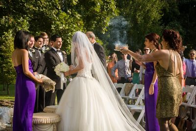 The mother of the bride offers burning espand as the bride walks down the aisle