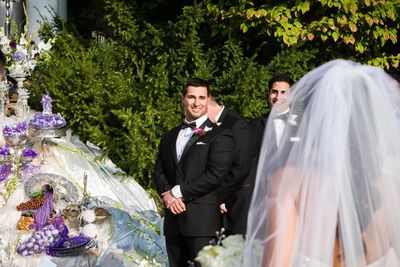 The groom with his calla lily boutonniere awaits his bride by the sofreh