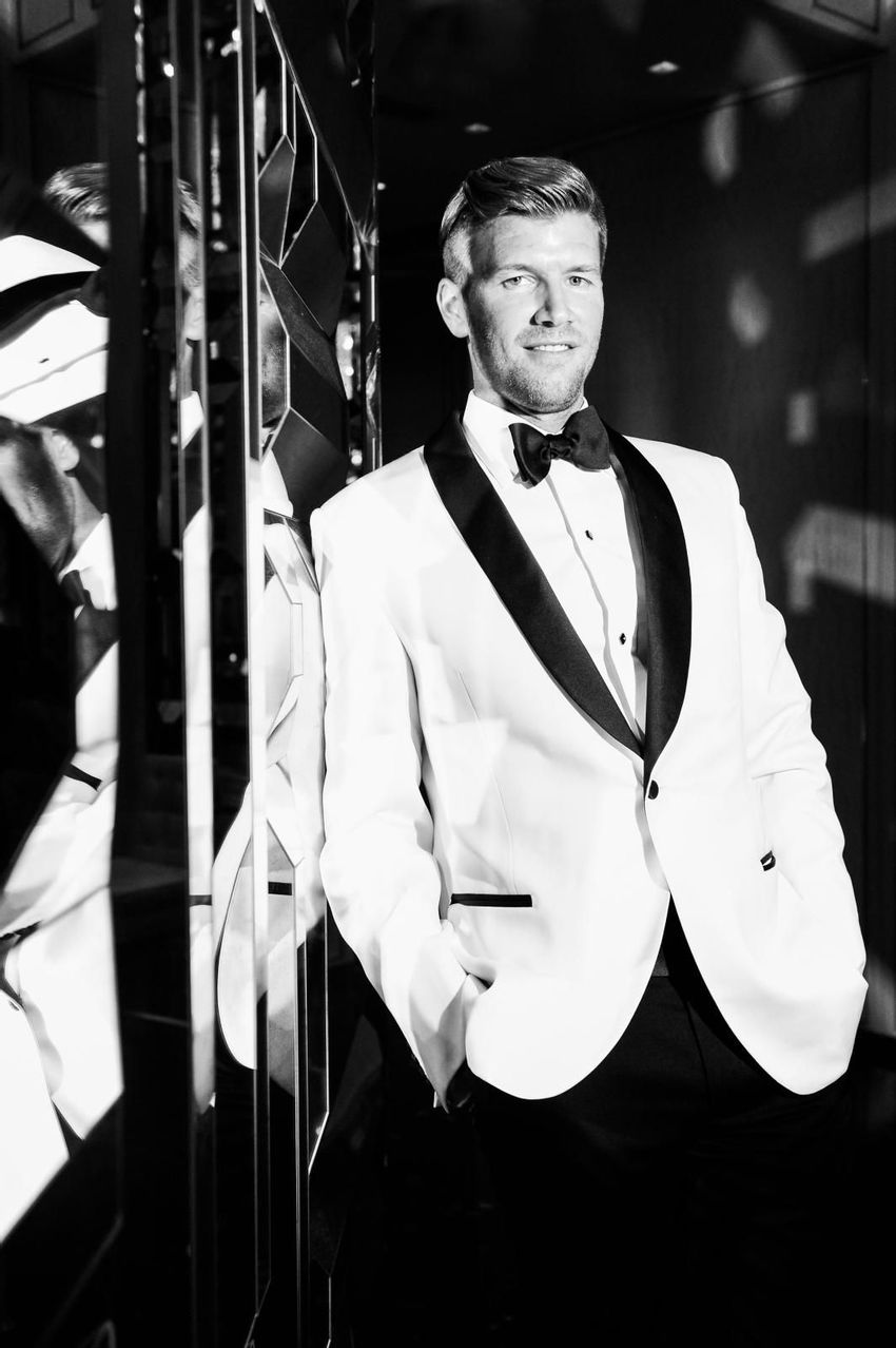 Groom's pose in his white tuxedo