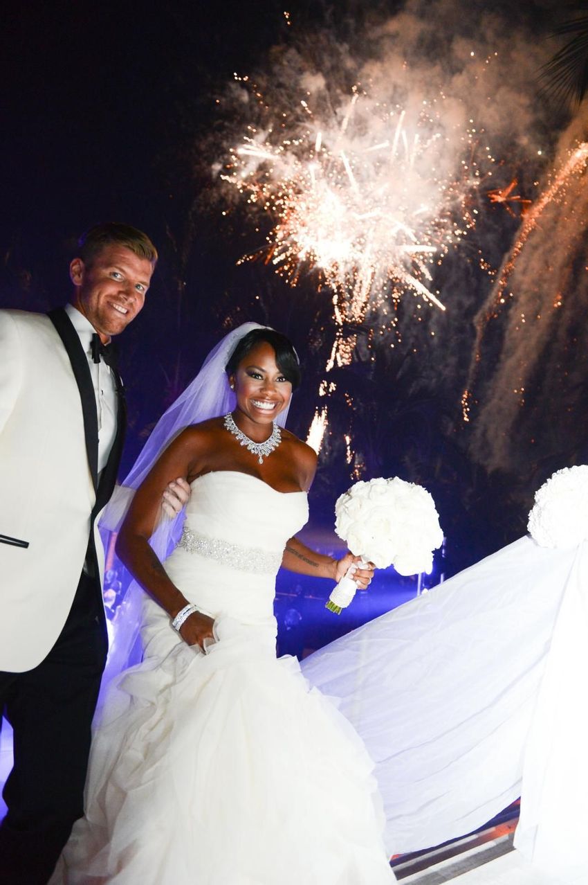 Happy bride while holding her all white peonies bouquet with his stylish groom in his white tuxedo 