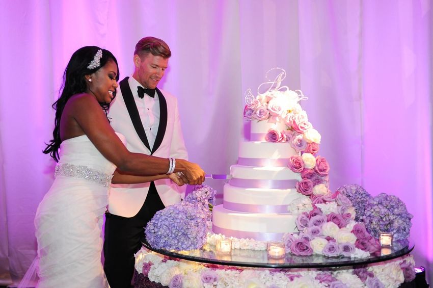 Couple's cutting their multi level wedding cake designed with fresh roses 